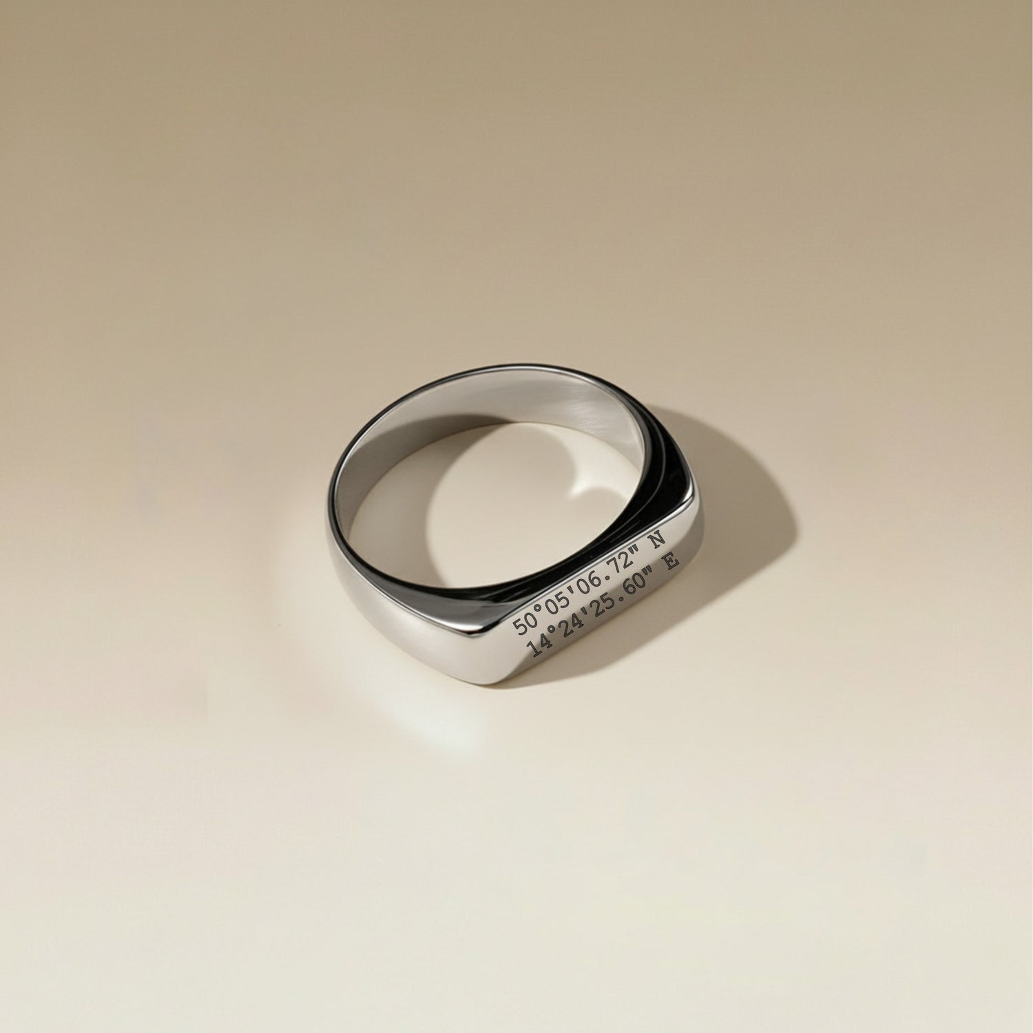 Silver ring with engraved text on a beige background