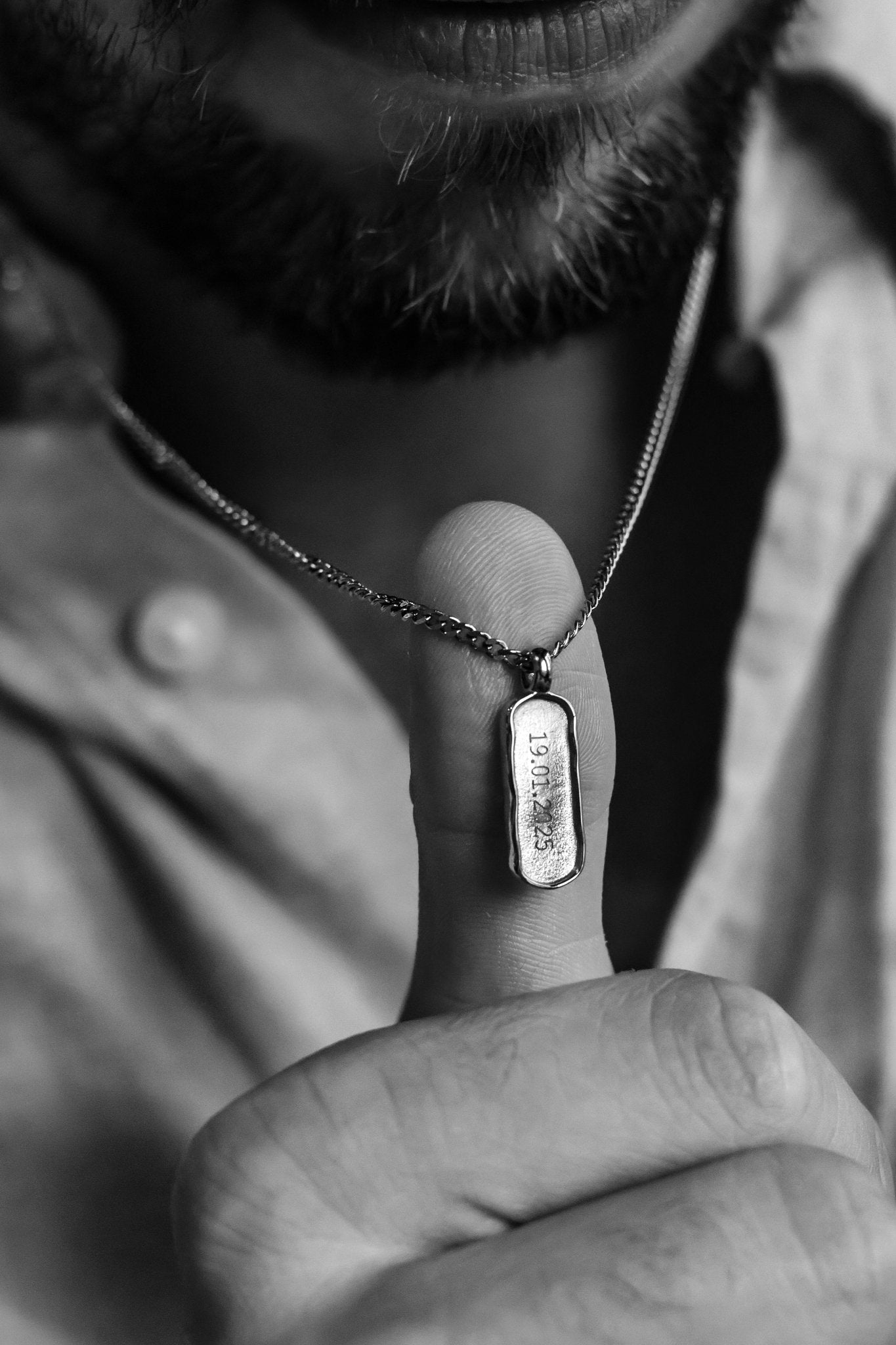 Close-up of a person holding a necklace with a pendant.
